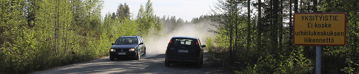 Henkilöautoja kulkee hiekkatiellä, tien pientareella yksityistien kyltti.