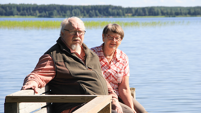 Esko Päivinen ja Leila Kontkanen istuvat laiturilla auringonpaisteessa.