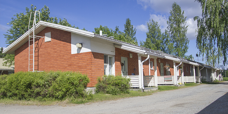 punatiilinen rivitalo koivuja taustalla aurinkoisena päivänä